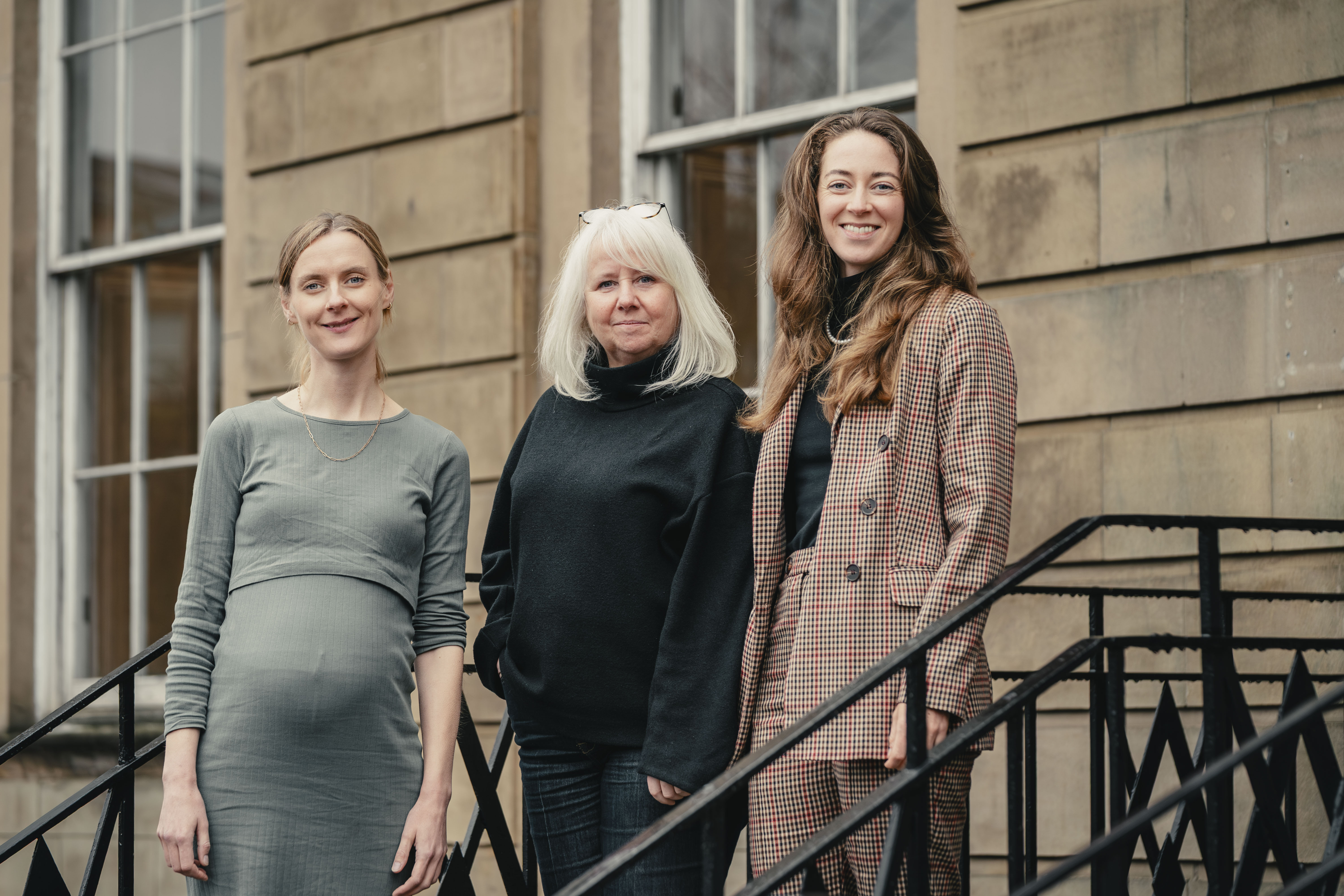 Three women posing in front of building